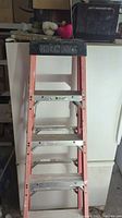 Front view of the 6 foot fiberglass ladder showing orange frame, aluminum steps, and black Green Bull top.
