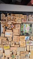 Photo showing a large collection of various wooden mounted rubber stamps arranged on a flat surface. The stamps have different holiday, floral, animal, and decorative designs.