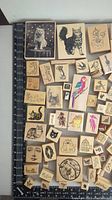 Top-down view of a large assortment of wood-mounted rubber stamps featuring animal and nature themes including cats, birds, fish, and floral patterns.