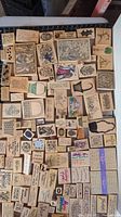 Top-down view of numerous wood-mounted rubber stamps with various sizes and designs, some featuring colorful ink marks.