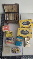 Photo of vintage first aid kit box open showing internal small boxes and various assorted boxed items including nails, locks, wire connectors, and small tools.