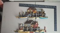 Two vintage molded plastic wall decor pieces depicting nautical themes with houses on piers, boats, and a lighthouse. A ruler placed nearby shows approximate size.