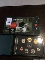 View of the black and green presentation box with the Royal Canadian Mint 2002 Specimen Set inside, showing all seven coins in a black foam holder with clear cover.