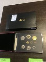 Black presentation box marked with Royal Canadian Mint emblem and gold maple leaf, containing clear plastic case with six coins arranged inside.