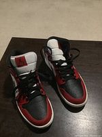 Pair of Jordan Air 1 sneakers viewed from front on wooden surface