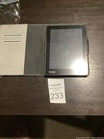 Kobo e-reader in protective cover displaying low battery indicator on screen with instruction to charge the device.