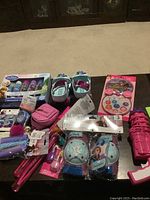 Lot of various little girl Frozen themed items displayed on the floor including shoes, jumbo chalk, lip gloss set, bracelets, and other accessories.
