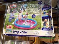 Front of the box showing children playing with the inflatable water pool with bucket and balls outdoors. Box highlights 25 balls included and suitable for children aged 3-5 years.