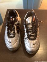 Top-front view of silver Nike Air Max 720-818 running shoes with black laces showing quilted upper and small Nike swoosh on the toe box.