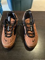 Front view of both Nike Air Max MX-720-818 shoes showing brown quilted upper with black laces and Nike swoosh on toe.