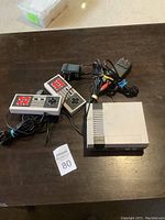Overview of mini retro gaming console with two wired classic style controllers on brown table.