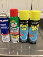 Four aerosol cans from left to right: ACDelco glass cleaner, Turtle Wax Power Foam remover, two Invisible Glass cleaners with yellow caps.