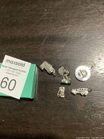 Six silver-colored bracelet charms including a dachshund dog, circular pendant, vintage car, glove, bouquet of flowers, and backpack.