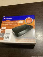 Front view image of Verbatim SuperSpeed USB 3.0 1TB Desktop Hard Drive packaging box showing product image and features.