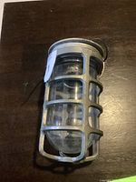 Top angled view of vintage metal safety cage enclosing a glass light bulb cover with attached handle.