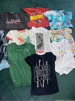 Photo showing 10 assorted graphic T-shirts in varied colors and prints, including Marvel, NASA and tie-dye designs