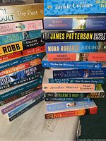 Stack of paperback books showing spines and titles of various novels.