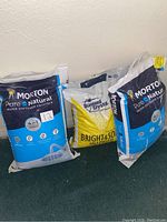 Three bags of water softener salt are shown together - two large Morton Pure and Natural 40 lb bags and one smaller Diamond Crystal 25 lb bag.