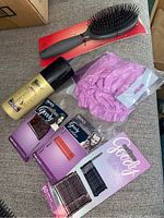 Overview photo of hair brush, Suave spray, purple hair cap in plastic, and three partial cards of bobby pins