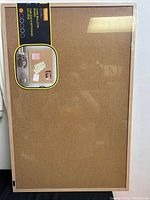 Front view of the cork bulletin board showing the natural cork surface and wooden frame, with packaging label attached.