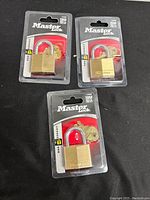 Three new Master Lock 140D padlocks in original packaging, displayed on black background.