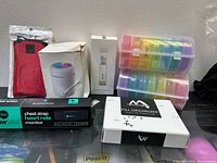 Overview of all items in the lot showing packaging for each accessory including pill organizers, heart rate monitor, cleaner, humidifier, and safety lock pouch.