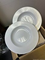 Two white ceramic soup/pasta dishes with wide rim and shallow bowl, displayed standing inside cardboard box.