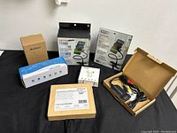 Full lot showing smartphone stands in packaging, Addtam USB-C adapter box, i72 earbuds in white box, power supply in open box, and HDMI splitter in brown box with cables