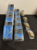 Full lot with 3 boxes each of screw hooks and screw eyes in blister packs, and 3 smaller boxes of brass turn buttons