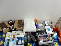 Photo showing two boxes of medium jar lids in brown color, Pottery Barn cream/off-white curtains sealed in plastic, Spot Shot spray can, glass bottles, broom holder, and other kitchen and household miscellaneous items.