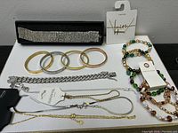 Full lot showing multiple jewelry pieces including bangles, chain bracelets, beaded necklaces, and fine chain jewelry all with new tags and packaging.