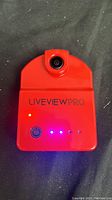 Front view of the red LiveView Pro golf training camera with lens and LED indicators.