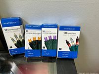 Four boxes of Northlight string lights, including 50 warm white mini LED lights, 50 orange LED wide angle lights, 50 purple LED wide angle lights, and 100 mini lights red and clear incandescent.