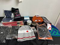 Lot contents showing winter hats, gloves, socks, candle, and grooming items neatly arranged on black surface