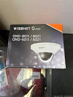 Box front showing Wisenet Q mini dome camera image with model numbers QND-8011, 8021, 6011, 6021