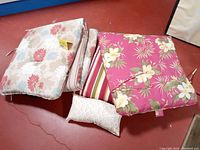 Lot showing two chaise lounge cushions and one yellow pillow on red floor.