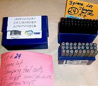 Three blue plastic boxes containing metal stamping tools with letters A-Z in script and uppercase styles, labeled by the seller with lot number and details.