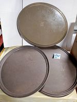 Two oval rimmed trays displayed, one larger leaning on the wall and one smaller in front.