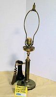 Full front view of the lamp showing black Western Electric phone handset attached to metal stand with lamp socket and harp, metal base with patina.
