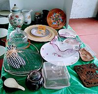 Photo showing assorted vintage glass and ceramic serveware arranged on green tablecloth.
