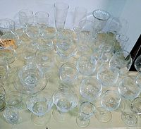 Clear glassware assortment on table showing multiple stemmed and non-stemmed glasses of various shapes and sizes.