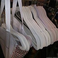 Full view of blush pink felt-covered hangers and other hangers on rack