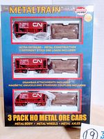 Front view of sealed box containing 3-pack metal ore cars with CN markings, showing red train cars and rock ore loads in blister packaging.