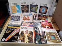 Full overview of all magazines laid on a surface showing a variety of Scientific American and American Scientist magazines with visible cover titles and illustrations.