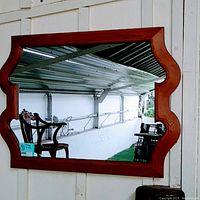 Front view of the large rectangular mirror with a curved wood frame showing the shape and finish of the frame with good reflective glass surface.