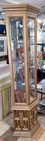 Full view of hexagonal vintage wood curio cabinet with glass sides, mirrored back, and panel door base with decorative woodwork.