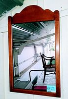 Front view of vintage wood framed wall mirror showing curved top shape and reflection.