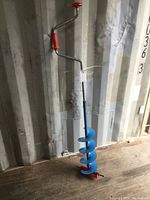 Photo showing full length of the blue 8-inch hand ice auger with red crank handle and blade cover.