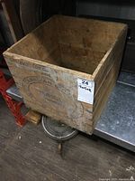 Top-front angle of old wooden butter box placed on metal surface, showing inner and outer sides.