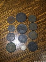 Top view of 12 assorted foreign antique coins showing various sizes, dates and worn surfaces.